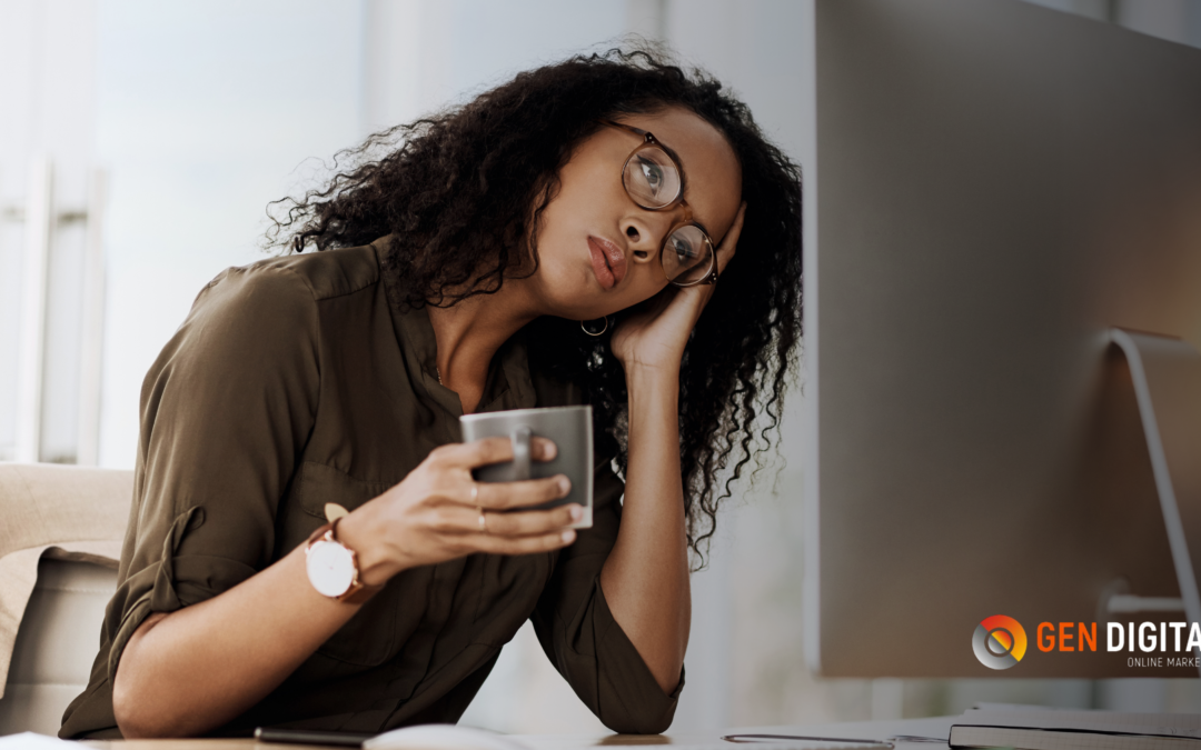 Mujer cansada frente a una computadora sosteniendo una taza de café mientras revisa una página web.